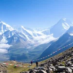 Trekkers on the Everest Base Camp Trek surrounded by towering peaks and colorful prayer flags.