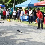 FOPI Kota Gorontalo community petanque event with players aiming boules in sunny outdoor setting.